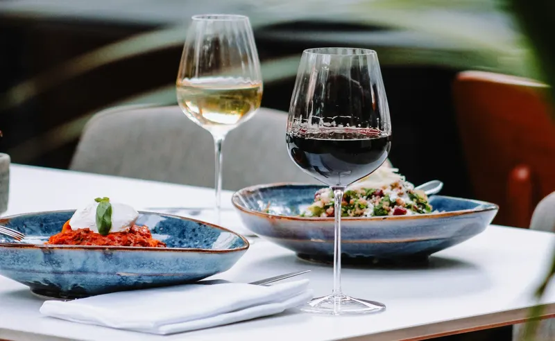 Table de restaurant avec un verre de vin blanc, un verre de vin rouge et deux plats dressés