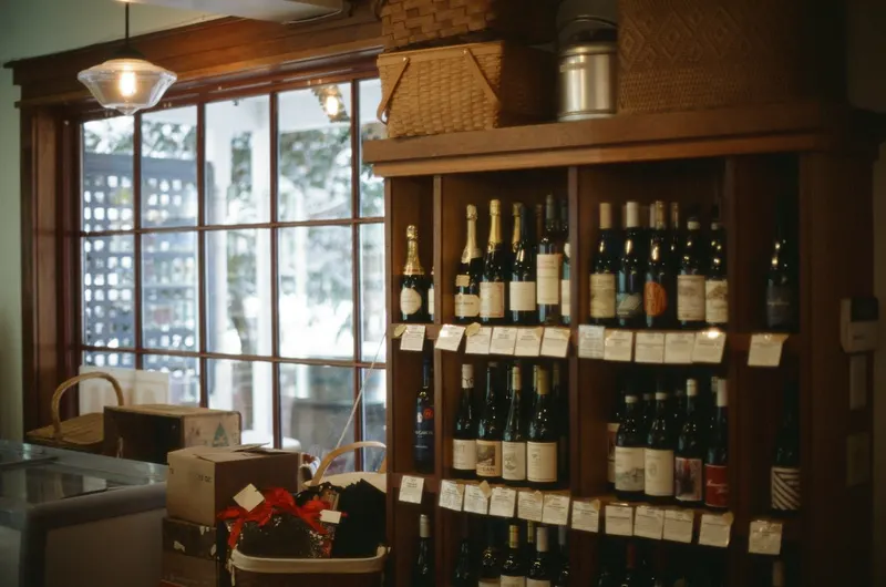 Wine bottles on wooden shelves with blank price tags in a small wine shop